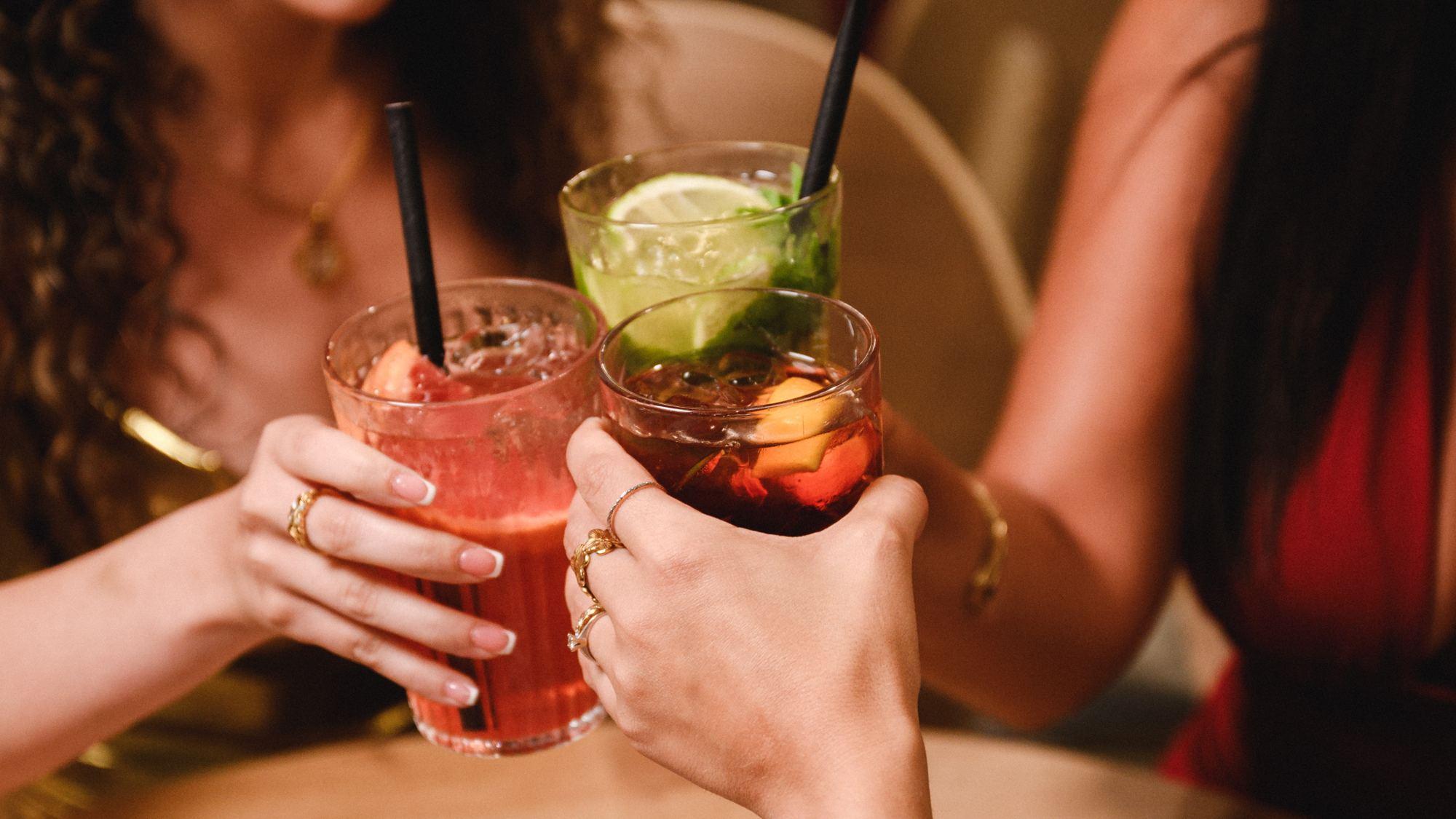 Three cocktails clinking at Saigon's Gżira bar during happy hour